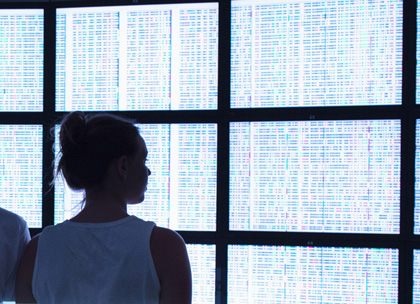 woman in silhouette looking at computer screens with genome data