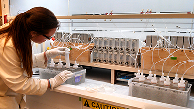 researcher in lab coat bending over instrument