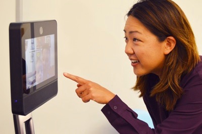 Photo of Leila Takayama interacting with a research assistant via robot