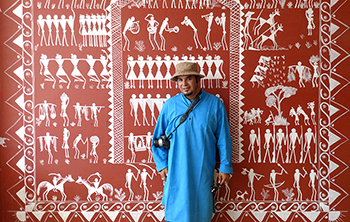 Ray Gutierrez and mural with tribal symbols