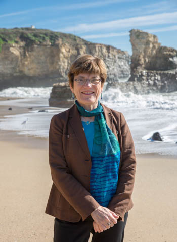 Anne Kapuscinski standing along the coast in front of breaking waves.