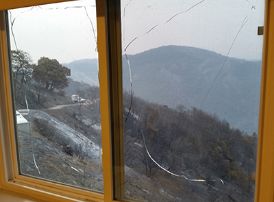 cracked window with view of burned hillside