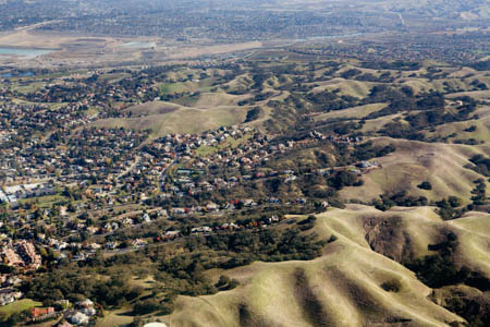 Aerial view of housing developments stretching out into rolling hills near the Santa Cruz mountains