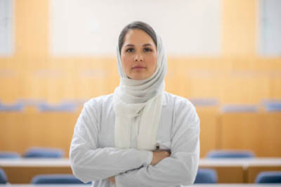 A woman wearing a religious head covering standing in an auditorium