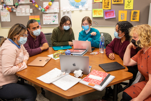 Students gathered around a table wearing masks