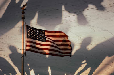 An American flag overlaid with the shadows of people