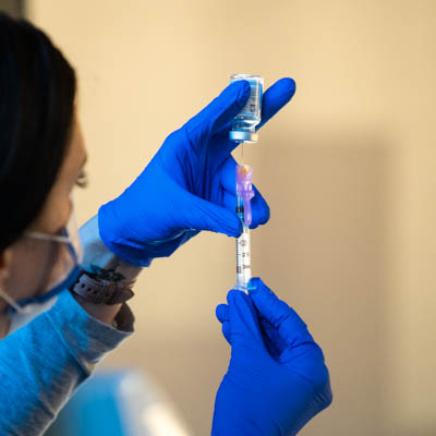 A health care worker filling a syringe with vaccine