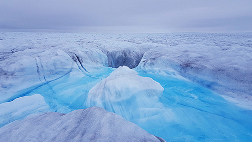 water flowing into crack in glacier