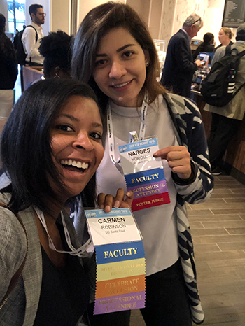 Robinson and Norouzi smile for a selfie and hold up conference badges.