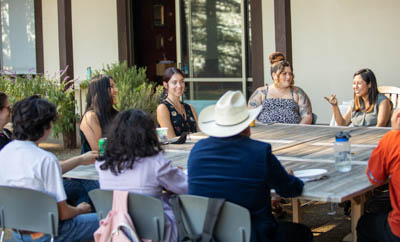 Cristina Jiménez and students sit outdoors around a table