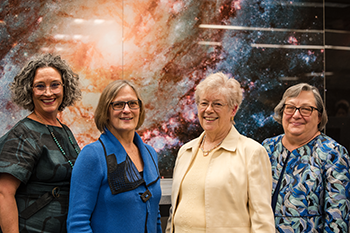 Campus leaders pose in front of an image of a nebula at the library dedication event. 