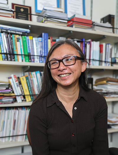 Portrait of Sri Kurniawan smiling in front of a colorful bookshelf. 