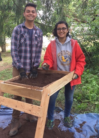 Photo of two students screening dirt in a search for artifacts at the Castro Adobe.
