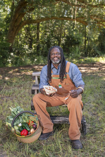Matthew Raiford sitting at a picnic bench on his farm with a bowl and fresh produce