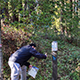 Students scans his phone to a AR marker in a wooded area on the UCSC campus.