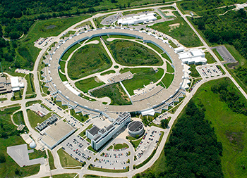 Pictured from above is a donut-shaped, concrete industrial facility surrounded by grass. 