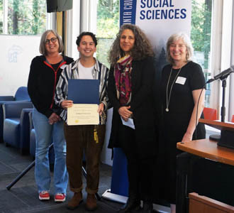 A student with an award certificate flanked by UCSC faculty and staff