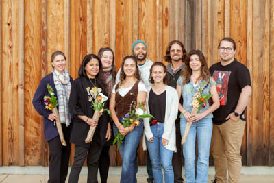 a group of people of all ages holding flowers in front of a barn