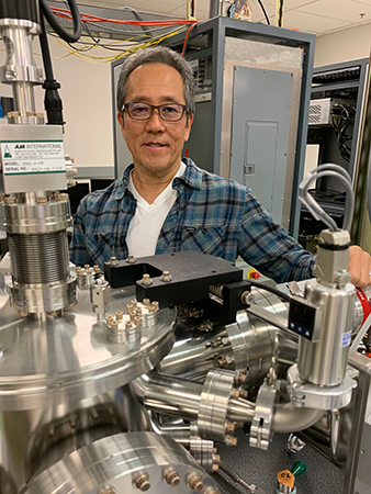 Nobby Kobayashi in his lab behind silver pipes and equipment.