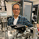 Nobby Kobayashi in his lab behind silver pipes and equipment.