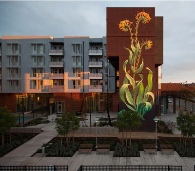 A mural of a wildflower on the side of an apartment building