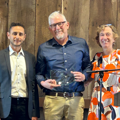 Kent Eaton holds an award plaque surrounded by colleages