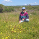 Karen Holl sitting in tall green grasses in an open field