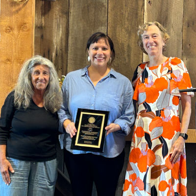 Cassie Isaacson accepts an award plaque, surrounded by colleagues