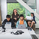 Sri Kurniawan stands behind a desk, where several students are working on computers