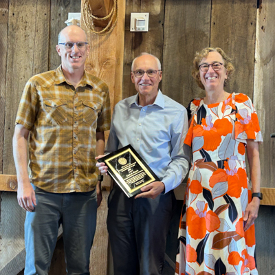 Carl Walsh accepts an award plaque, surrounded by colleagues