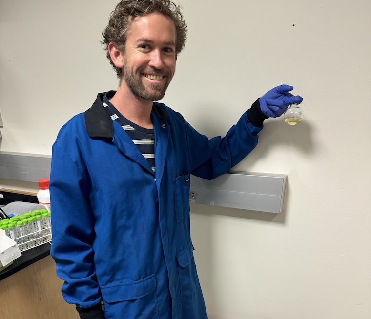 Kevin Lofgren in lab holding flask of biodiesel