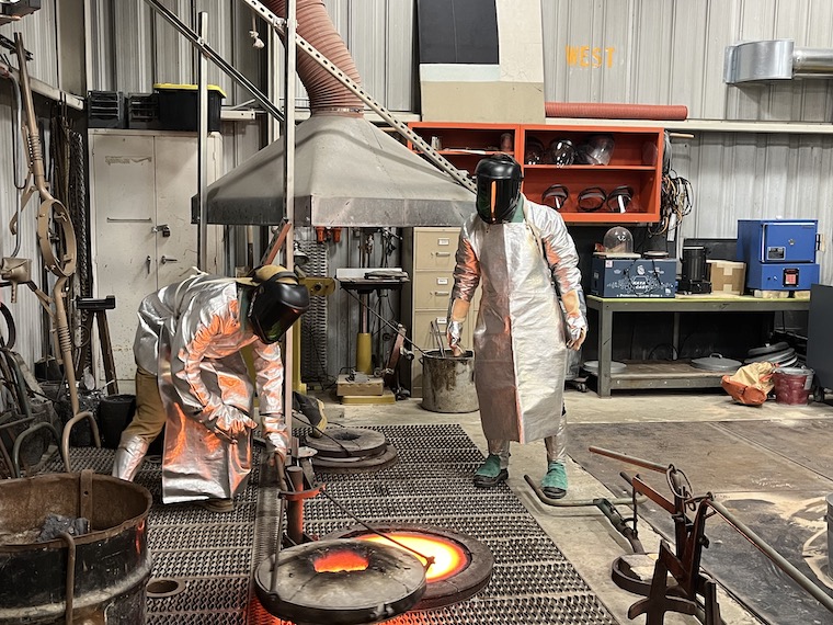 Foundry director Sean Monaghan and an assistant work with hot bronze to create sculptures