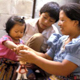 A woman and children work together to play with a wooden puppet toy