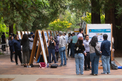 People explaining research findings on poster boards to a crowd