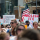 Protesters march holding signs saying "abolish ICE"