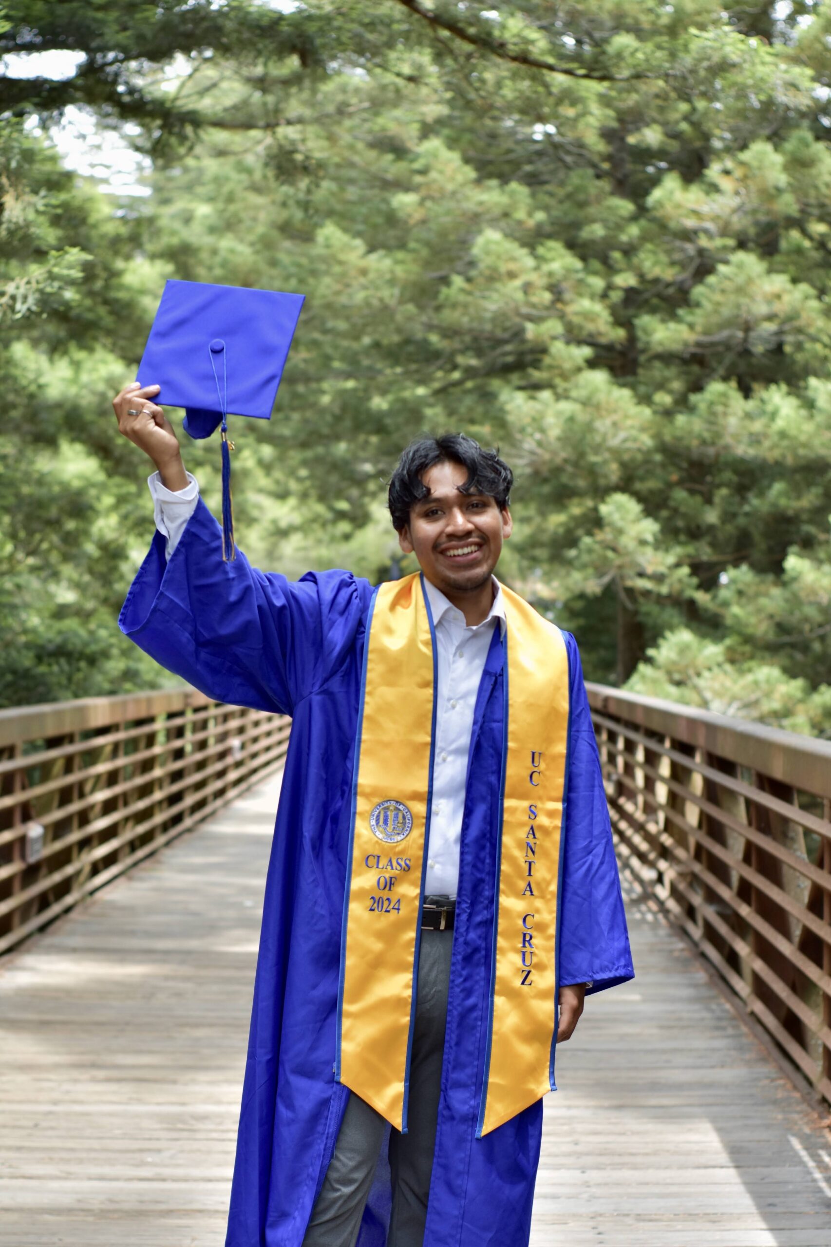 Danny Cruz poses for a graduation photo on a bridge at UC Santa Cruz.