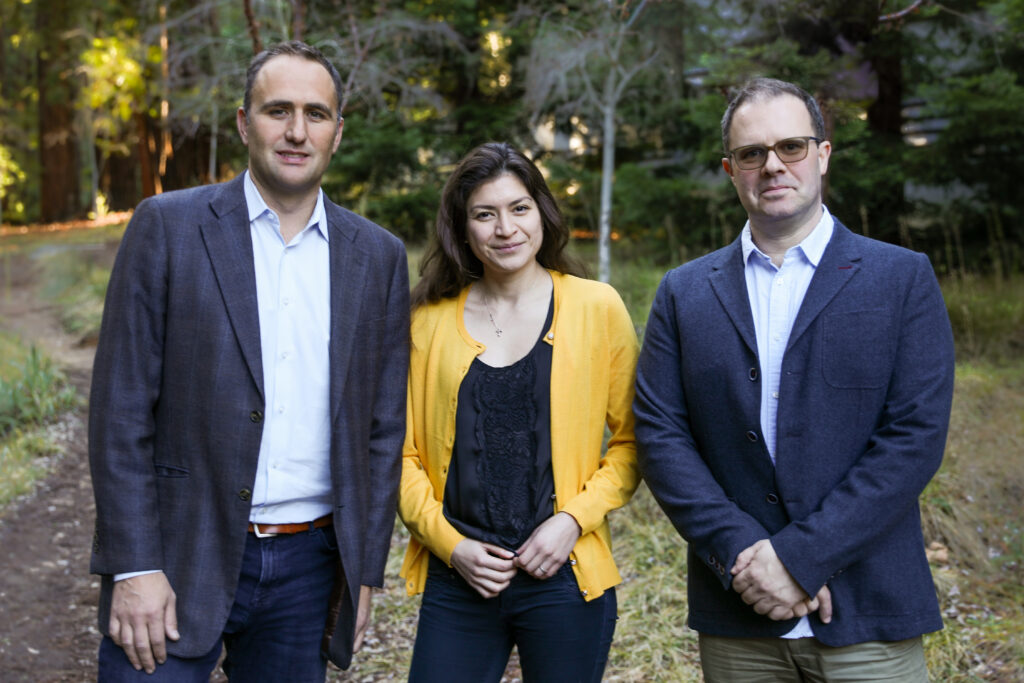 Rolandi, Gomez, and Teodorescu stand side by side against a  wooded background