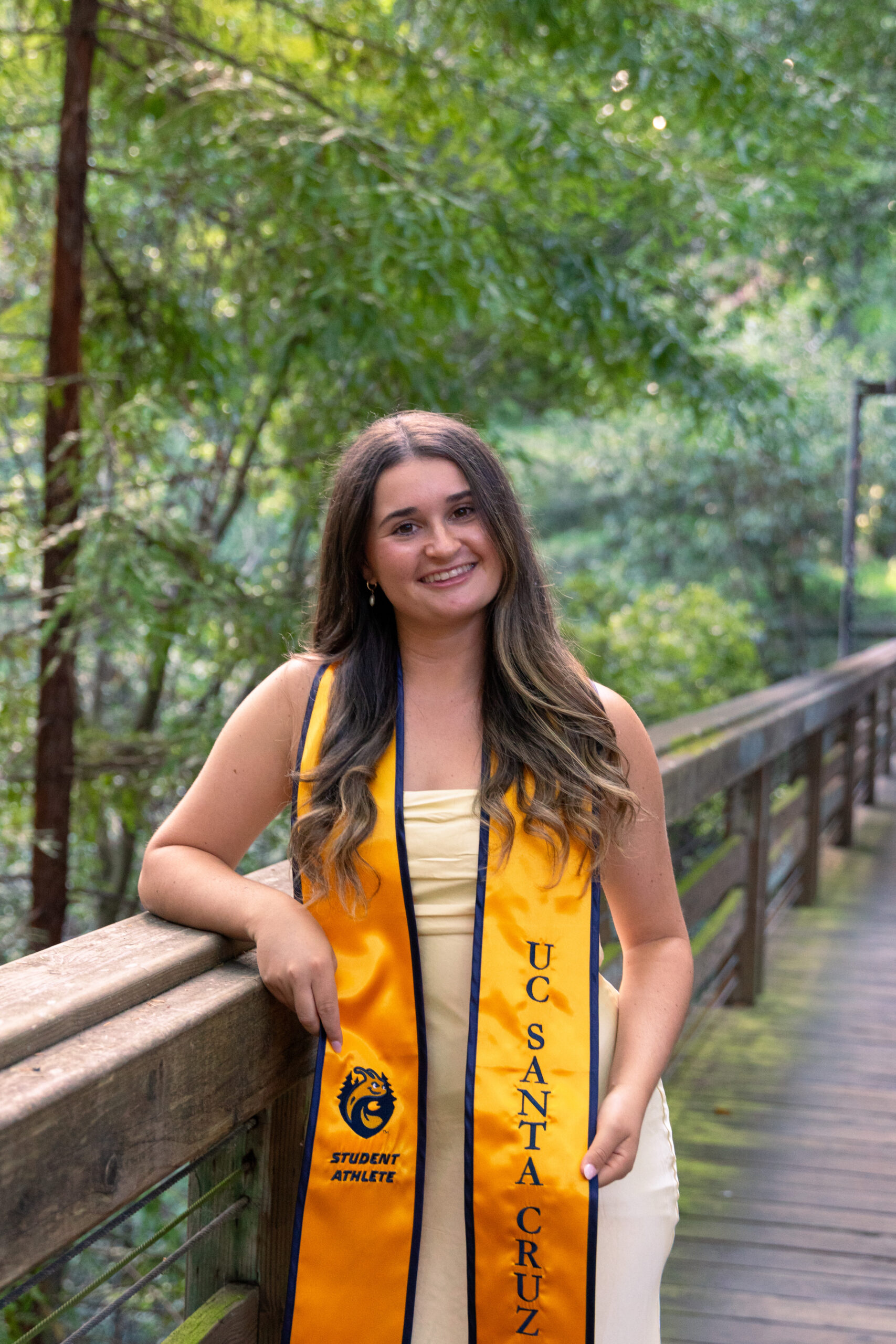 Tanner Rowland poses for a graduation photo on a bridge at UC Santa Cruz.