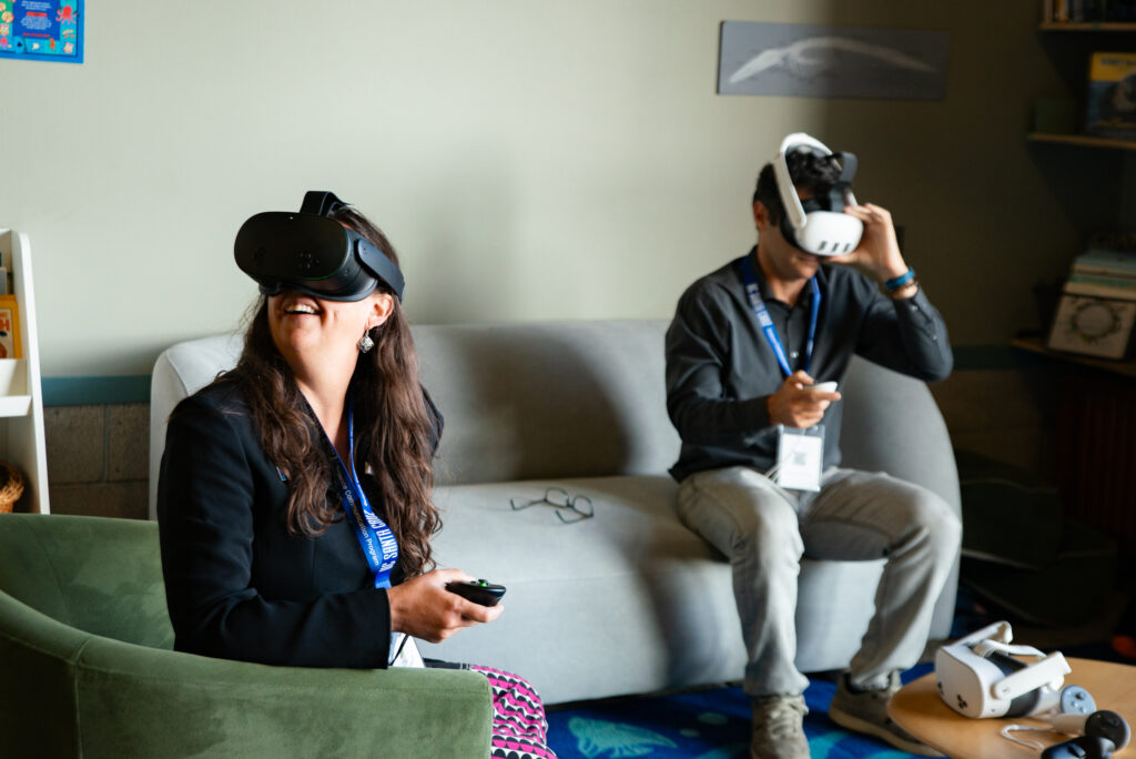 Two symposium attendees seated and wearing VR headsets