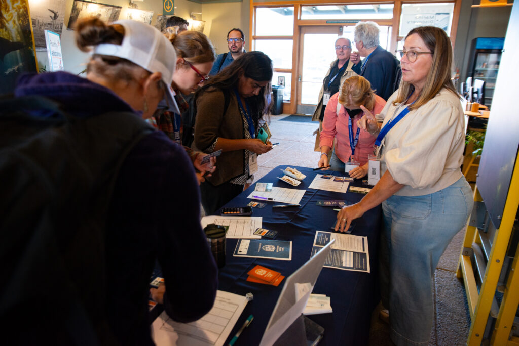 Santa Cruz Sustainability and Resiliency Officer Tiffany Wise-West showing symposium attendees climate-themed games on a table