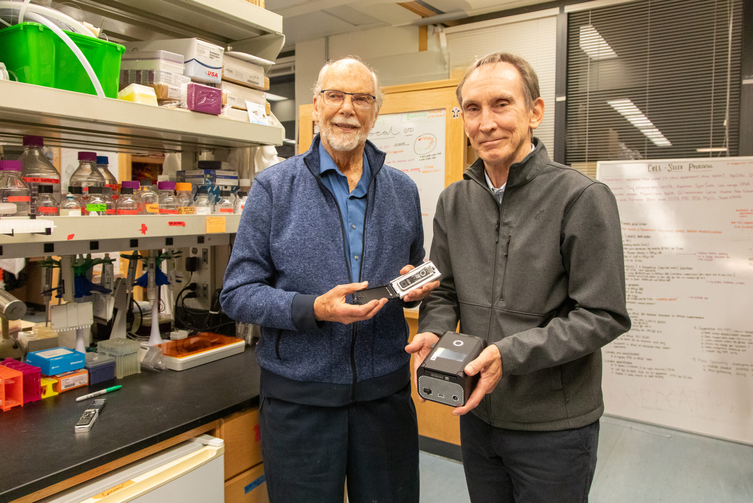 David Deamer and Mark Akeson hold up electronic devices in the lab.