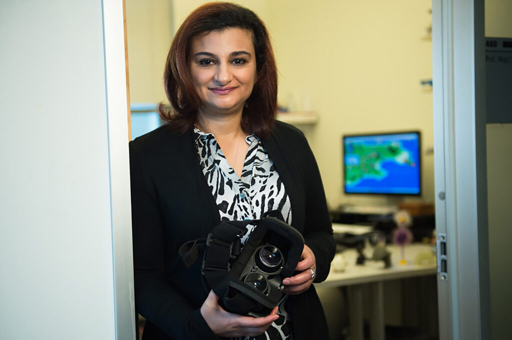 Magy Seif El-Nasr stands in a doorway holding a VR headset.