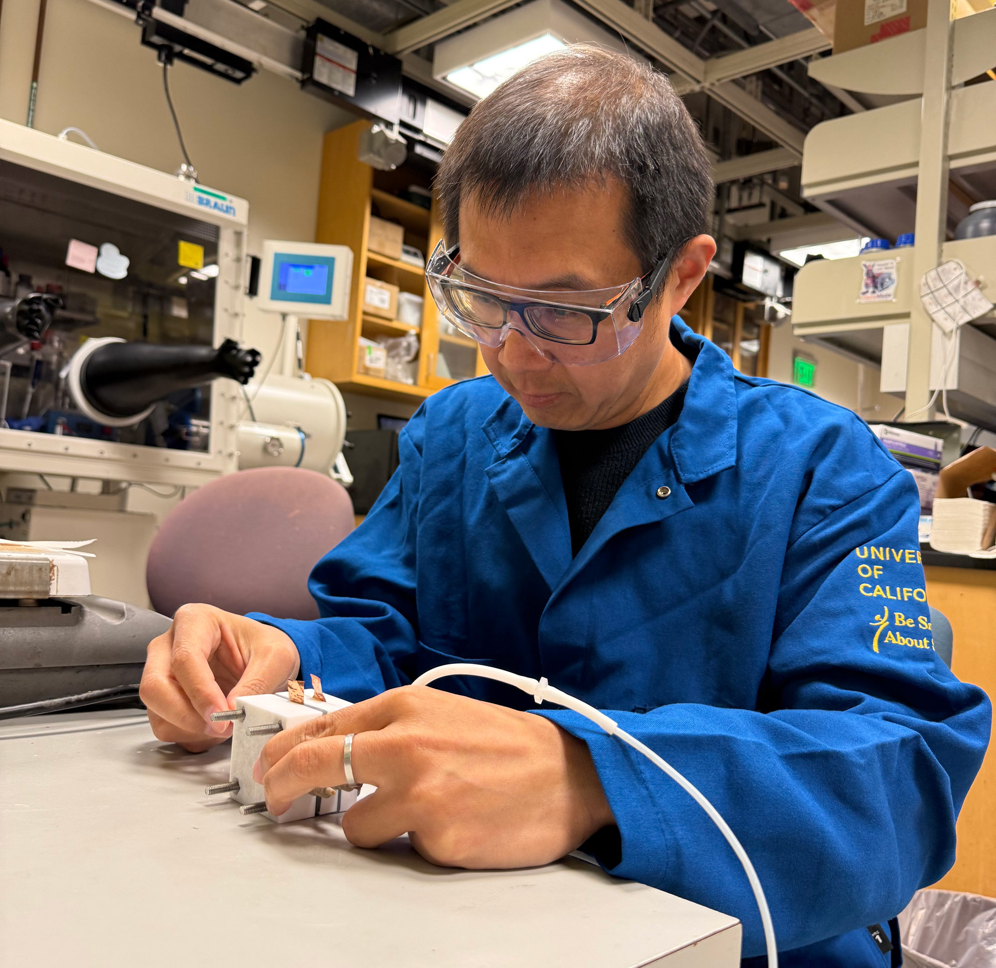 Yat Li is working in the lab with goggle and blue lab coat