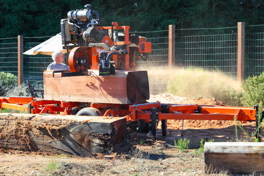 Man on a portable sawmill processing a piece of redwood.