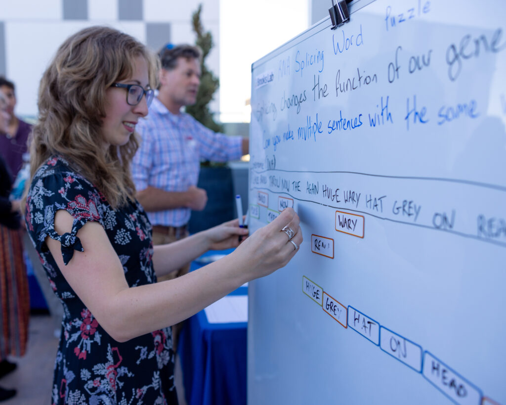 A female graduate student demonstrates RNA splicing using a word game on a board