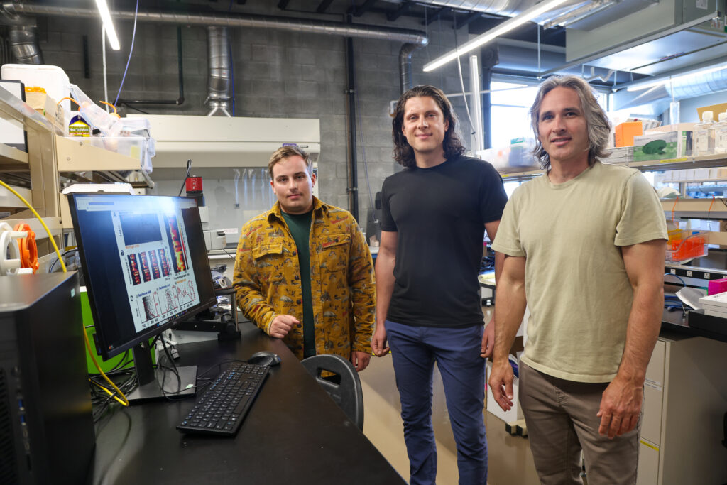 Three researchers smile at the camera in the lab.