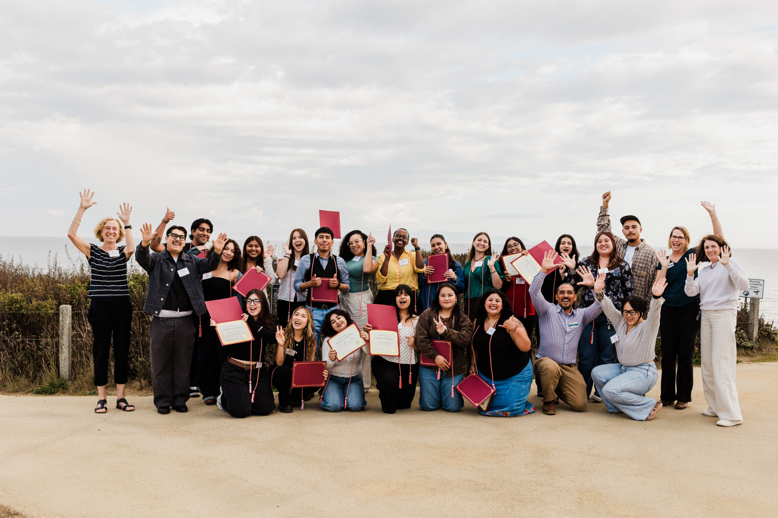Group photo of people cheering while holding certificates of completion