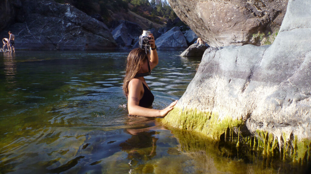 student in lake holding a camera