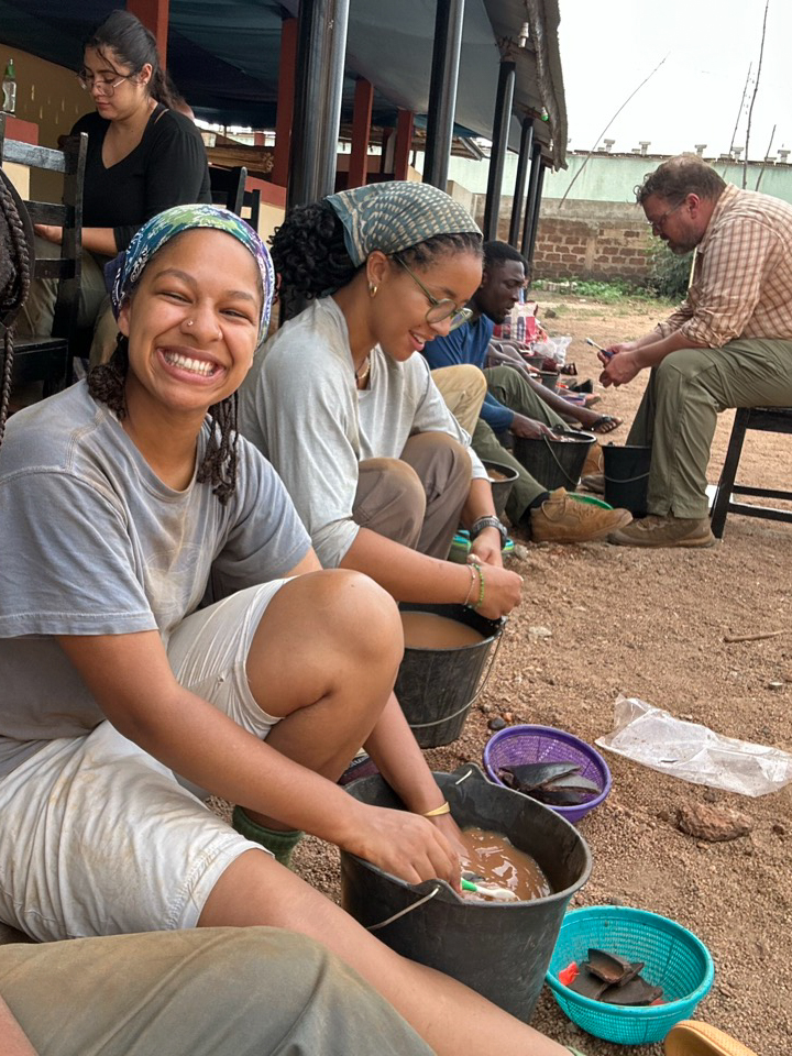 Students wash artifacts with toothbrushes in buckets