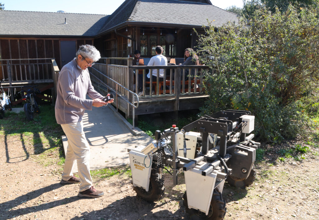 A man leans over a small tractor